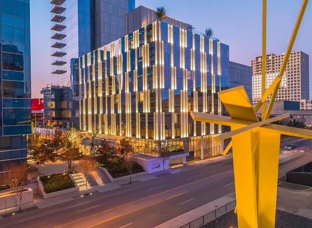 The HALL Arts Hotel&rsquo;s glass front lit at dusk, with a yellow sculpture in the foreground.