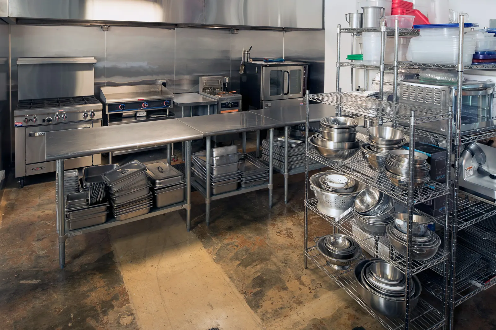 The prep line: steel range, griddle, convection oven and racks of bowls and hotel pans.