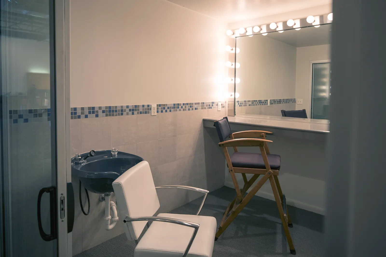 The makeup room: a lit mirror, a director's chair and a hair-wash station.